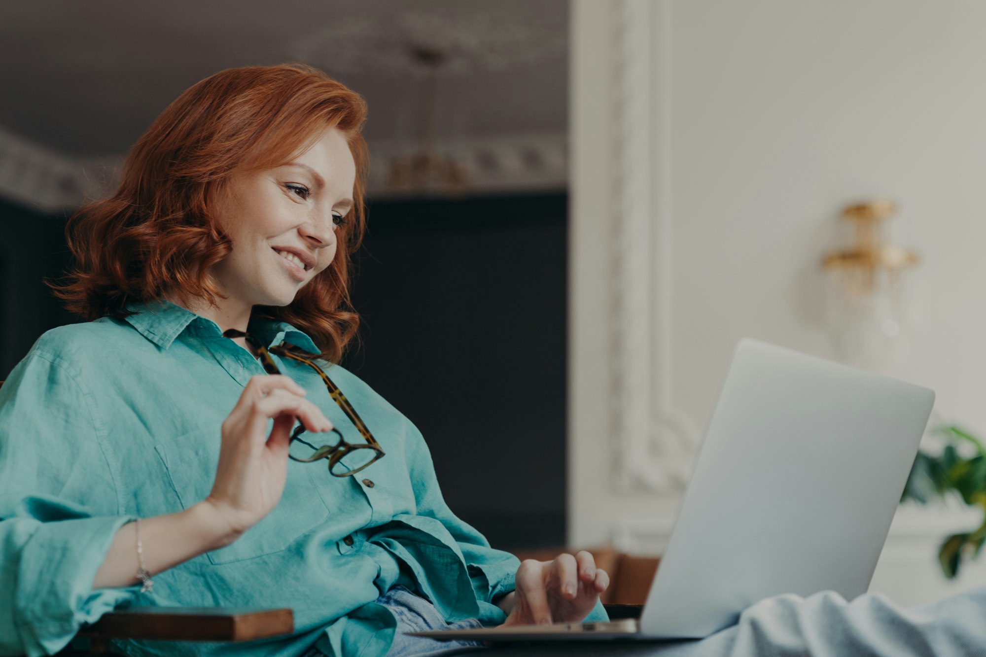 Side view of pretty redhead woman concentrated on remote job, prepares publication for web page